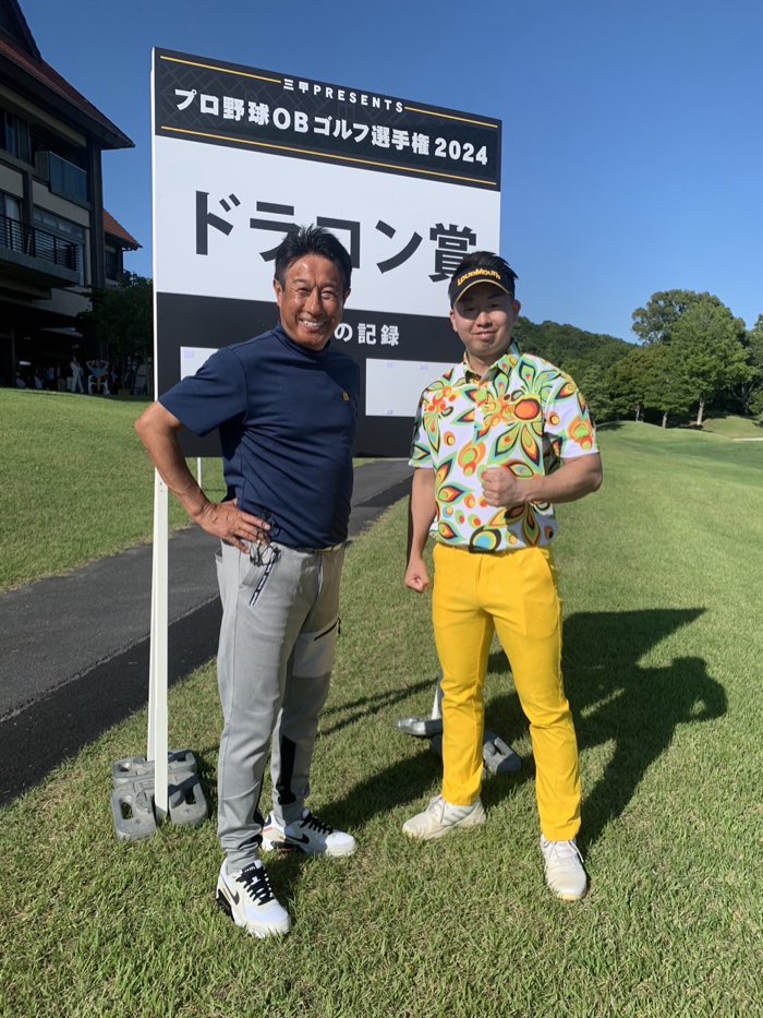 プロ野球OBゴルフ選手権2024のドラコン賞の看板前に立つ谷朝陽コーチ
